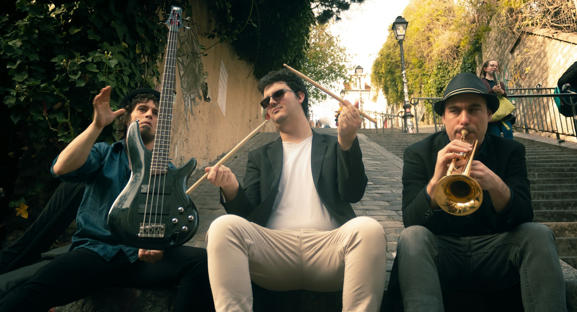 three men playing musical instruments while sitting on ramp beside stairs